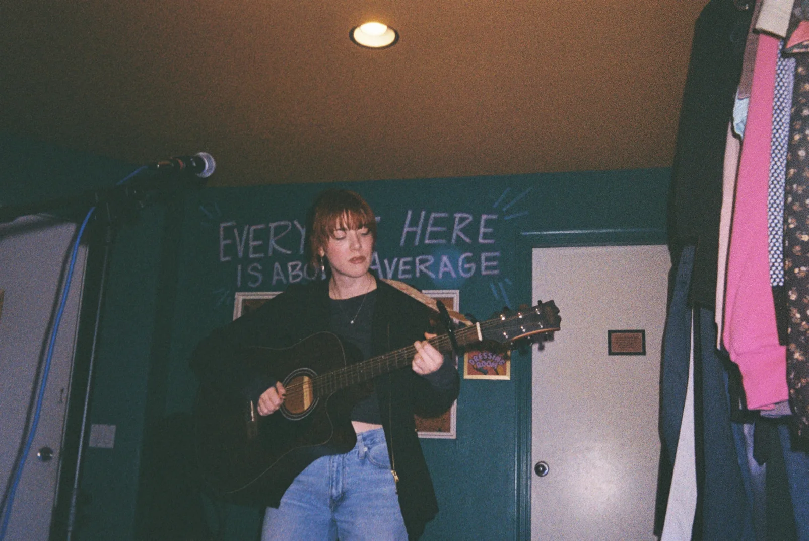 Bree Cole performing with an acoustic guitar in an intimate venue