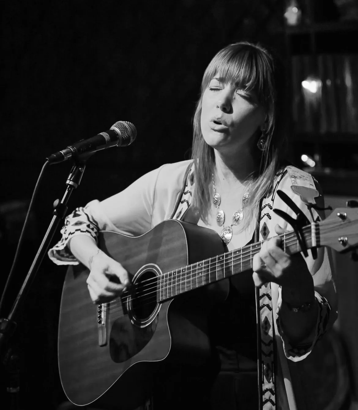 Black-and-white portrait of Bree Cole singing with an acoustic guitar